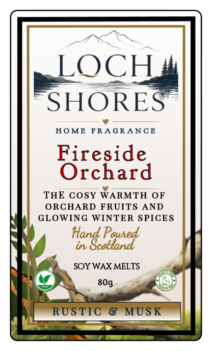 Front of a Loch Shores Home Fragrance 'Fireside Orchard' soy wax melts package, 80g. The cream-colored label features a scenic landscape illustration of mountains and a lake, with text highlighting the cozy, warm, rustic, and musk notes of the fragrance.