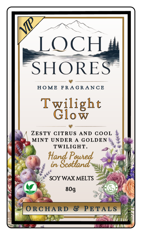 Front label of Loch Shores Home Fragrance 'Twilight Glow' soy wax melts, featuring a cream background with black and gold typography, a mountain and lake illustration, and floral fruit illustrations along the bottom.